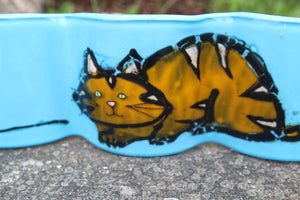 Close up of glass art featuring a ginger and gold cat