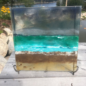 A handcrafted beachscape glass panel in an iron stand