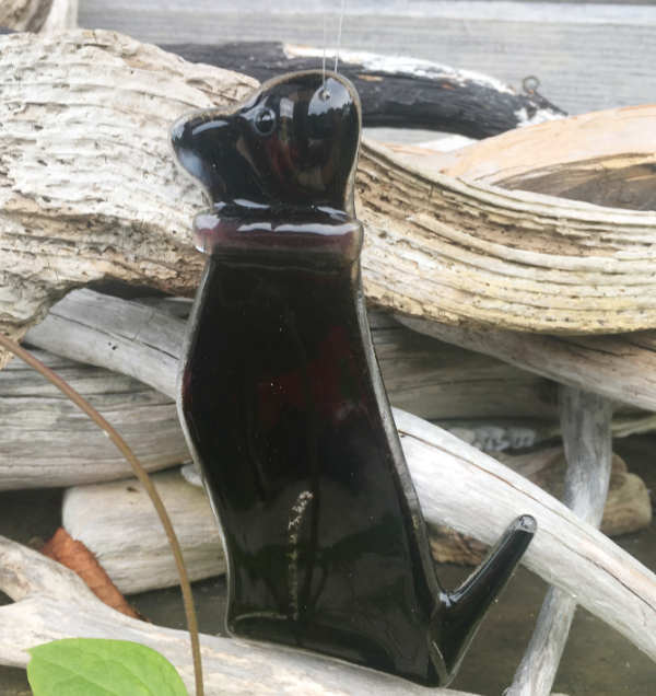 Black glass dog with a white moustache and purple collar. 