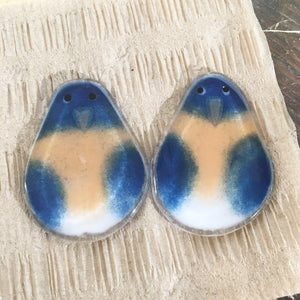 A pair of fused glass bluebird ornaments face the camera