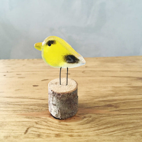 A pocket sized goldfinch made of yellow and black glass