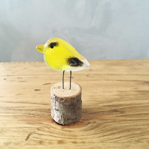 A pocket sized goldfinch made of yellow and black glass