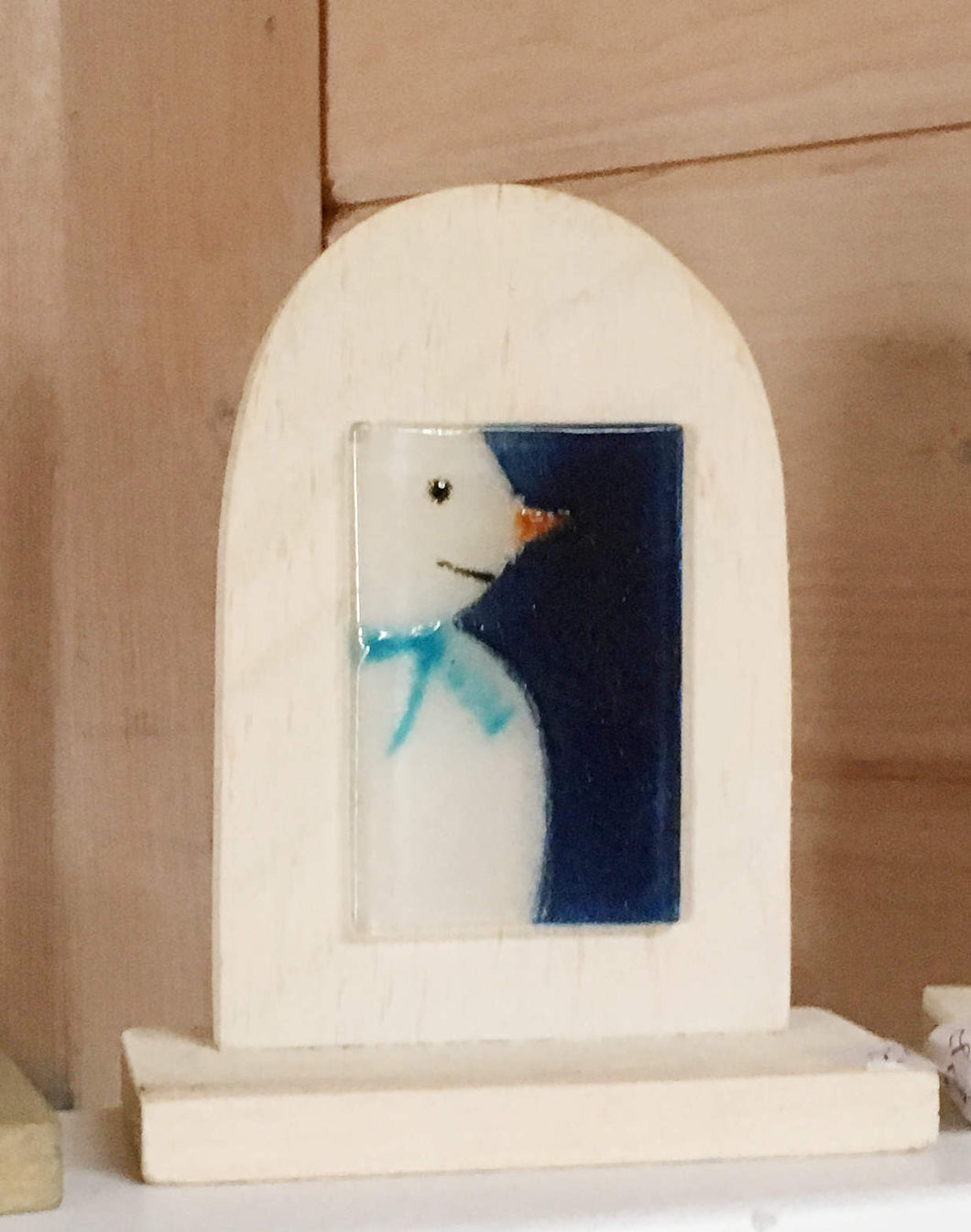 Table Top Ornament: Glass picture tile featuring snowman in blue scarf, mounted on a wooden white arch
