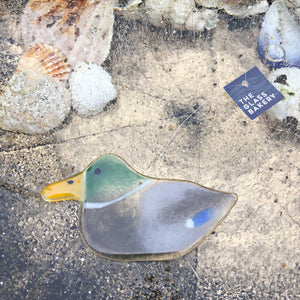 Hanging Glass Mallard Duck Ornament on ice background with seashells.
