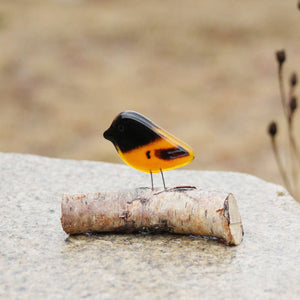 Orange and Black Baltimore Oriole Chick made from glass and perched on a  log