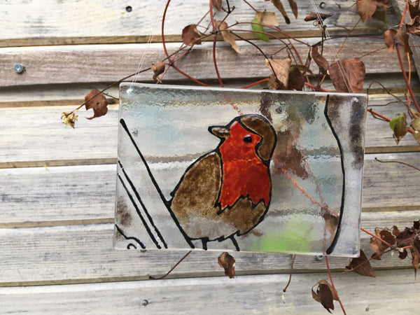 Charger l&#39;image dans la galerie, A glass tile featuring a British Robin. The tile hangs against a natural backdrop of winter clematis. 
