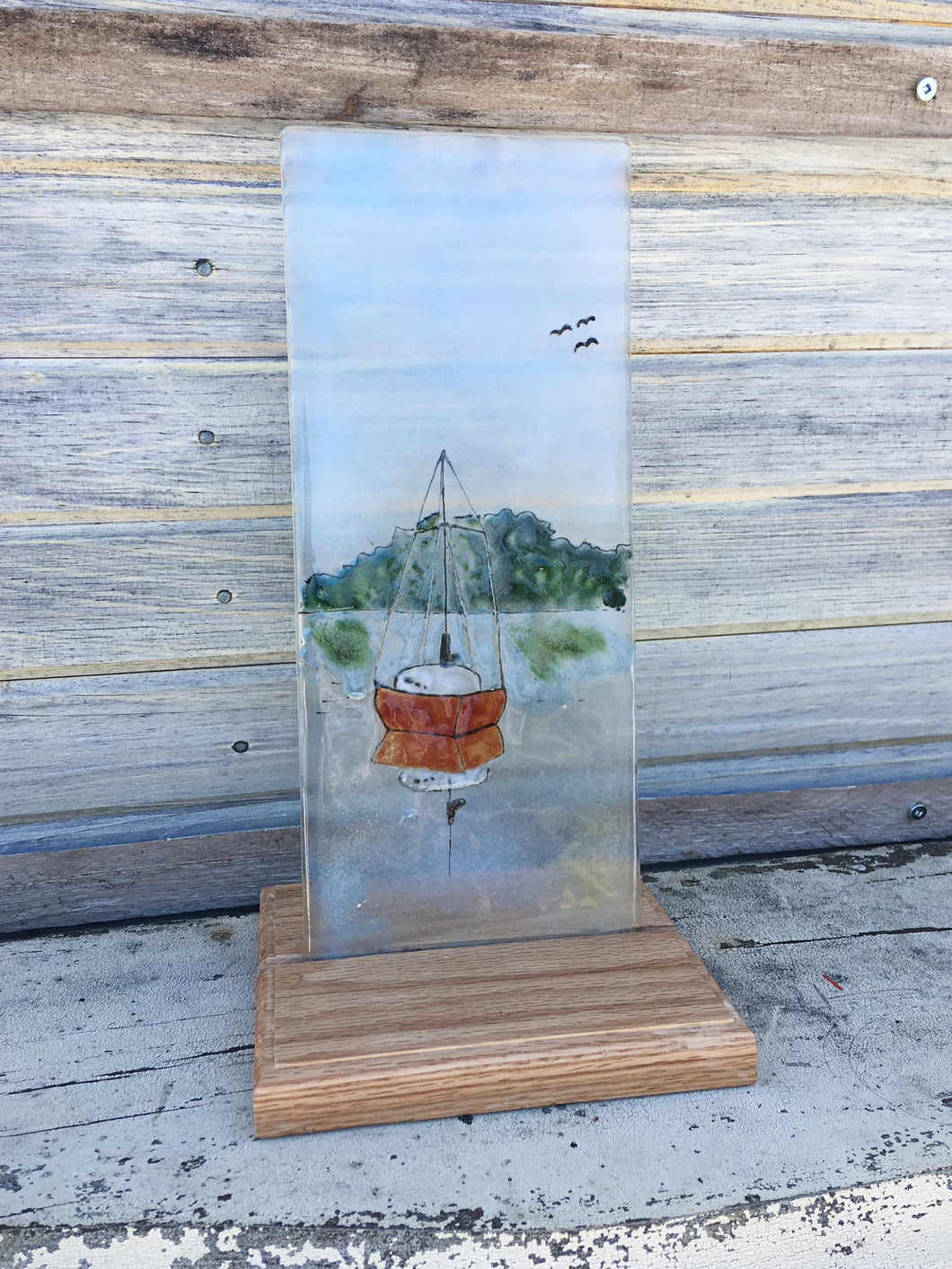Glass picture of a red sailboat. 