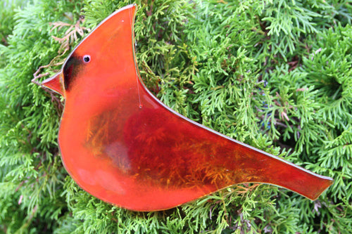 Large red glass cardinal bird hanging art piece, with cedar tree in background