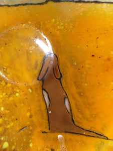 Close up of amber glass dish showing brown and white dog