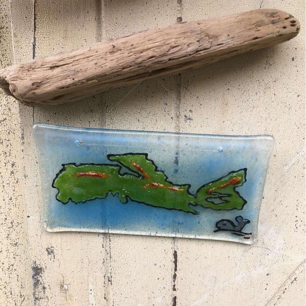 Glass picture tile showing the outline of Nova Scotia and a whale. The tile hangs from Driftwood